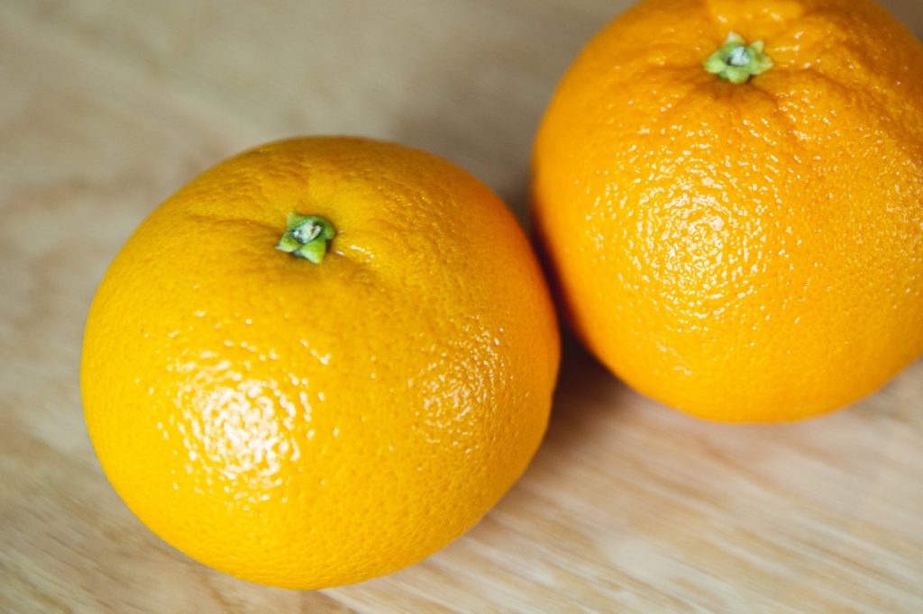 bright whole ripe oranges on wooden table